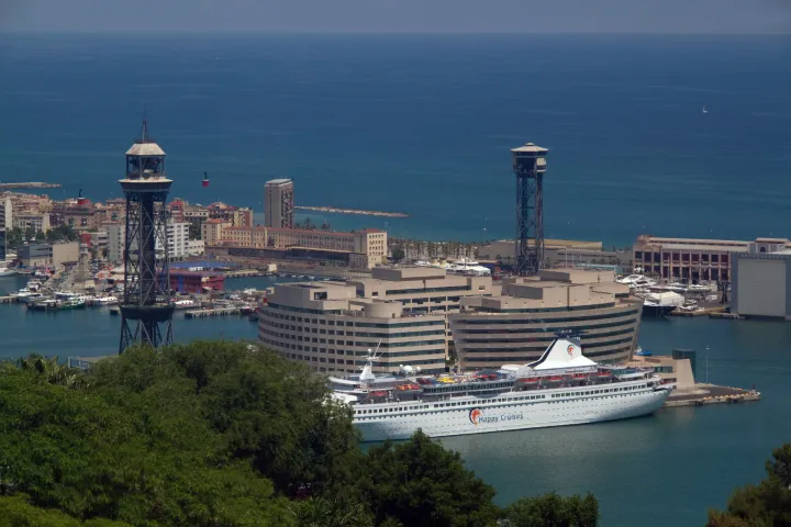 Um navio de cruzeiro atracado em frente ao World Trade Center, com a Torre Jaume I do teleférico, visto de Montjuïc