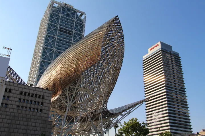 O Peixe Dourado de Frank Gehry, uma estrutura de metal que brilha ao sol, em frente ao Hotel Arts e à Torre Mapfre