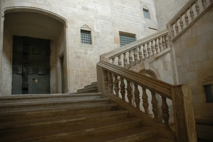 L'escalier Renaissance du patio du Palau del Lloctinent, sa rampe à balustres de pierre et le portail sculpté du palier