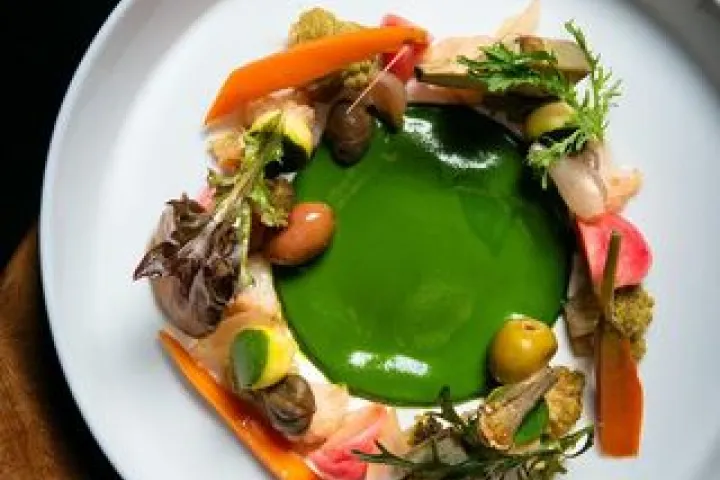 Colorful vegetables arranged in a circle around a green sauce.
