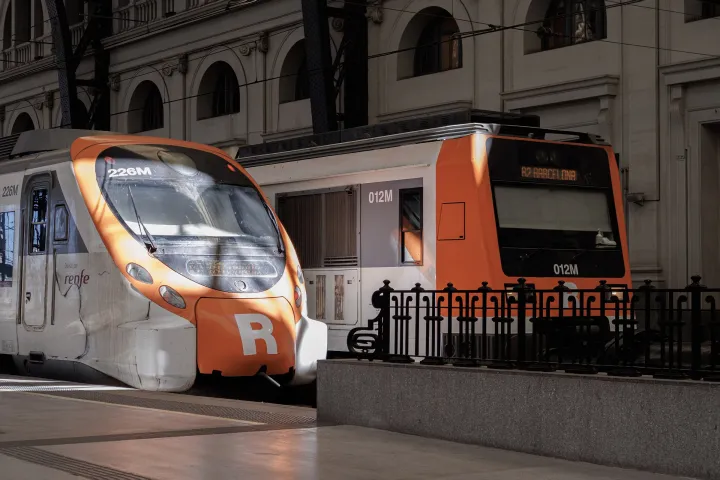 Deux trains de banlieue Rodalies orange et blanc, dont un Civia et un R2, sous la verrière de l'Estació de França