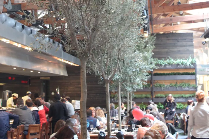 La sala del restaurante Cuines de Santa Caterina, sus olivos y su cocina abierta bajo la estructura de madera del mercado