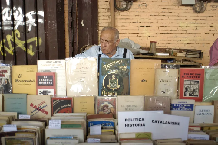 Ein Buchhändler auf dem Sonntagsmarkt von Sant Antoni hinter seinen Tischen mit alten Büchern