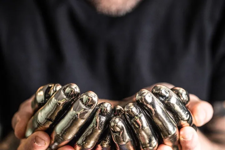 Ein Barkeeper präsentiert einen metallischen Behälter in Form von gefalteten Händen.