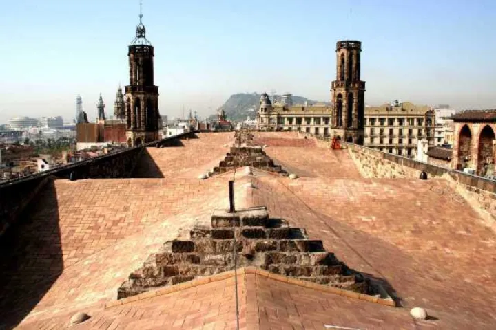 Desde la terraza de Santa Maria del Mar, el techo de tejas se extiende hacia los dos campanarios, con los tejados del Barrio Gótico y las colinas de Barcelona en el horizonte