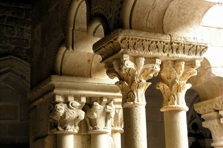 A row of sculpted capitals in the cloister, blending vegetal motifs and animal figures