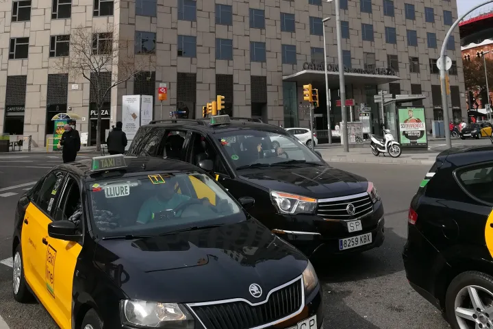 Trois taxis noir et jaune à une station de la plaça d'Espanya, le panneau Lliure visible sur le pare-brise du premier
