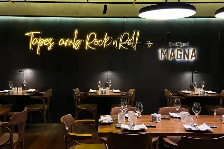 Tables set in a room with dark walls, under a neon sign reading "Tapes and Rock'n'Roll."