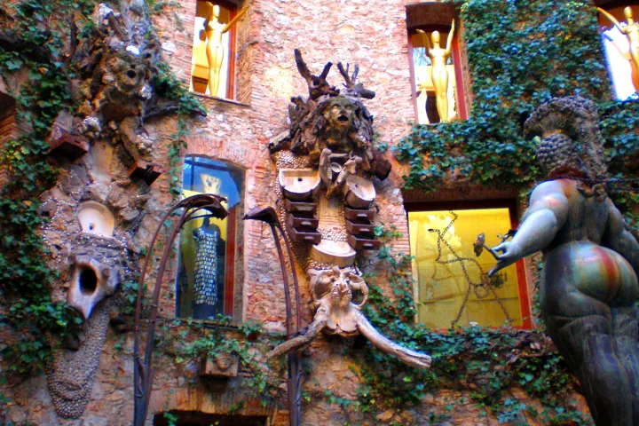 Les murs de la cour du théâtre-musée de Figueres présentent des arcades, des fenêtres et des statues dorées.