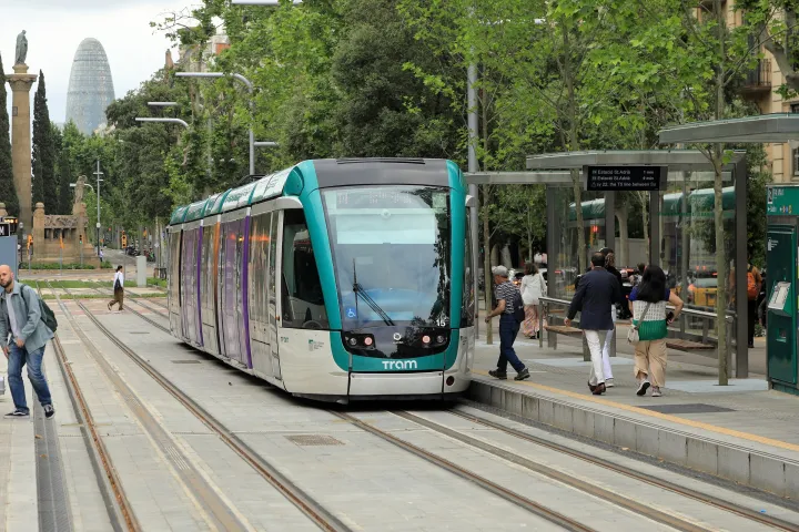 Tram Citadis verde e bianco della linea T4 alla fermata Verdaguer, con la Torre Glòries sullo sfondo