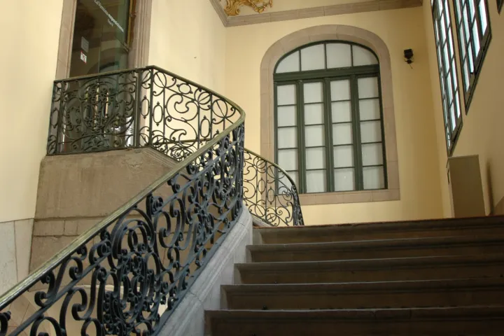 L'escalier d'honneur du palais de la Virreina, sa rampe de fer forgé et le lustre suspendu au plafond doré