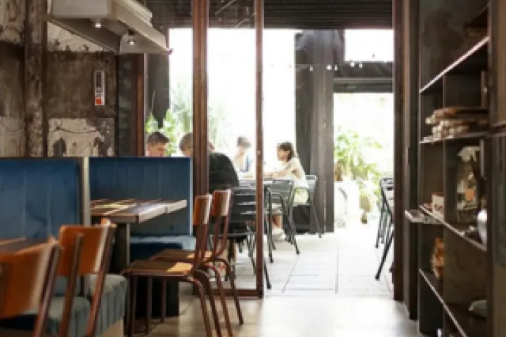 Vrutal dining room with wooden tables and a bright opening onto the street.