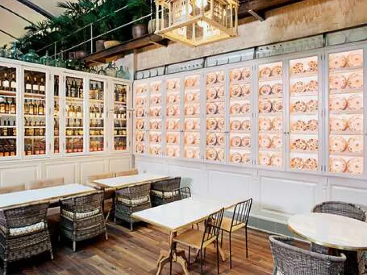 Coin repas d'El Nacional avec chaises en osier, panneaux décoratifs et grande lanterne suspendue.