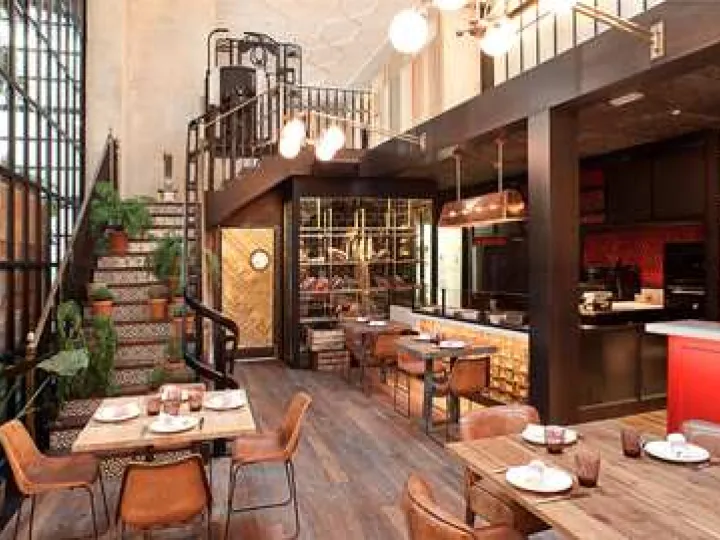 Tables dressées près d'une grande verrière, d'un escalier carrelé et d'un comptoir rouge à El Nacional.