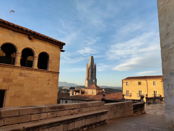 Der Glockenturm von Sant Feliu erhebt sich über die Ziegeldächer, zwischen steinernen Gebäuden.
