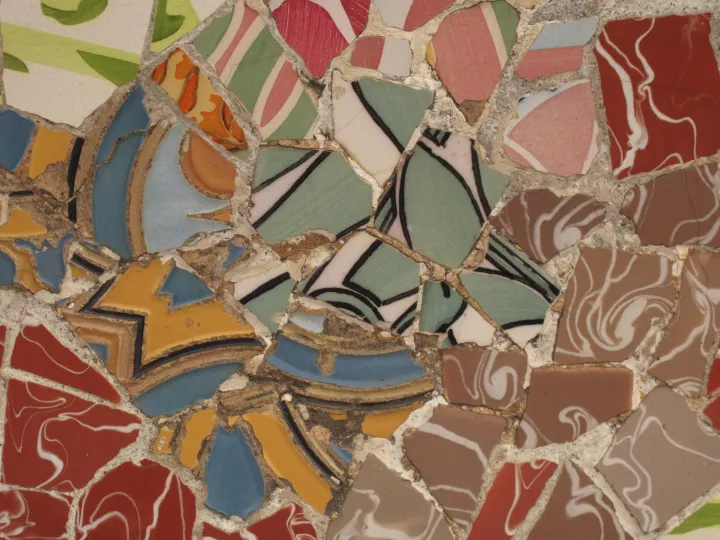 Fragments de céramique rouges, bleus et ocre assemblés en trencadís sur le banc ondulé