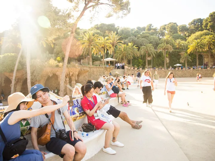 Visiteurs assis sur le banc ondulé de la place de la Nature, au Parc Güell