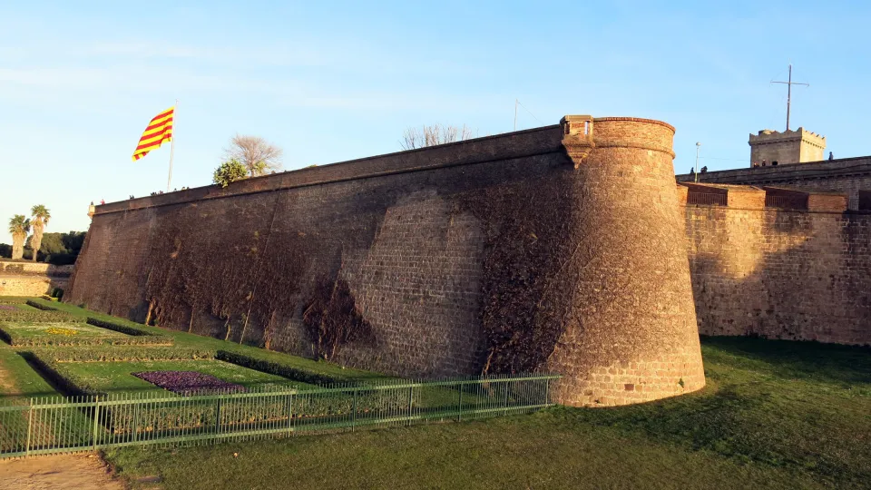 El bastión de Santa Amàlia del castillo de Montjuïc, su muro en glacis y su garita redonda, bajo la bandera catalana