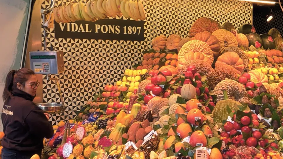 Une vendeuse devant les pyramides de fruits colorés de l'étal Vidal Pons, à la Boqueria