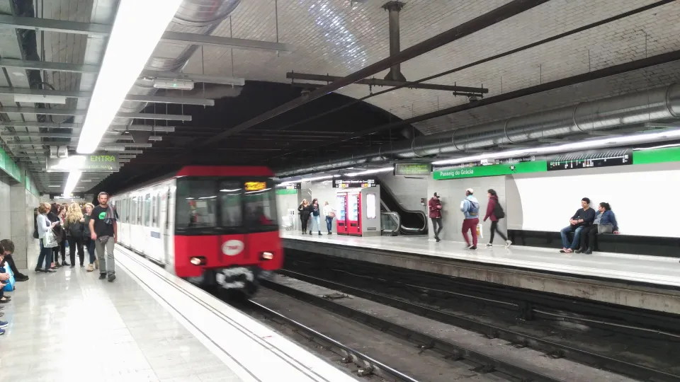 Rame de métro rouge et blanc entrant en station Passeig de Gràcia (L3), voyageurs sur les quais