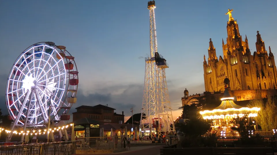 A roda-gigante iluminada, a torre da Talaia e o templo do Sagrat Cor ao entardecer no topo do Tibidabo