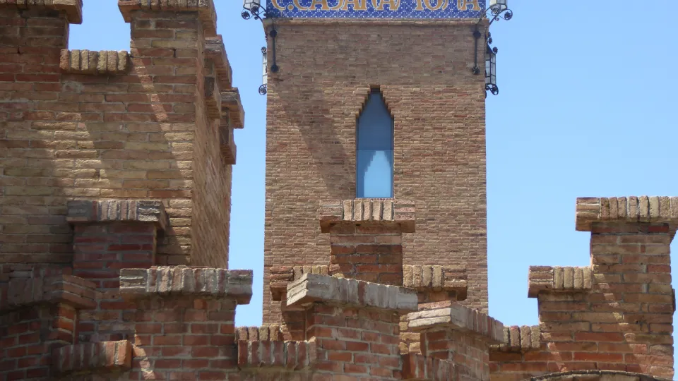 The crenelated brick rooftops of the former Casaramona factory and its tower with the ceramic sign
