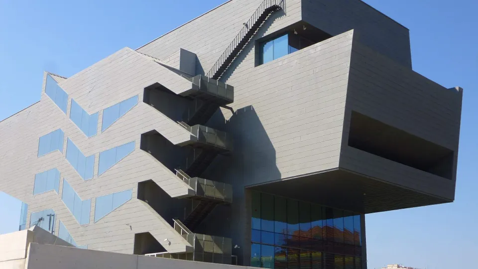 O edifício cinza do Disseny Hub, com seus volumes em balanço e suas escadas externas em zigue-zague