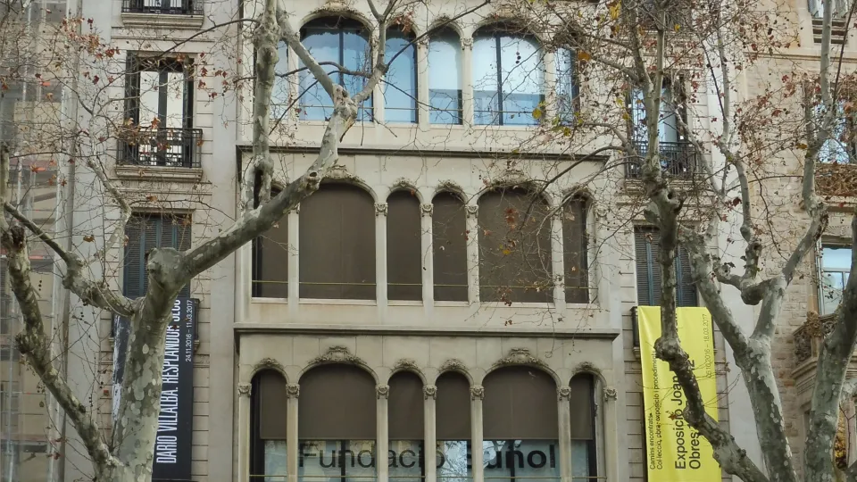 Die Fassade des Gebäudes am Passeig de Gràcia, das die Fundació Suñol beherbergt, hinter den Platanen