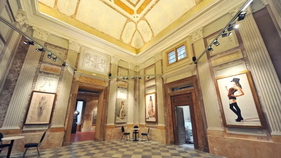 A room with gilded moldings and a painted ceiling, a marble checkerboard floor, where large contemporary portraits are hung