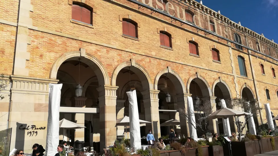 La façade en brique du Palau de Mar, ses arcades et le nom du musée en grandes lettres, avec les terrasses en contrebas