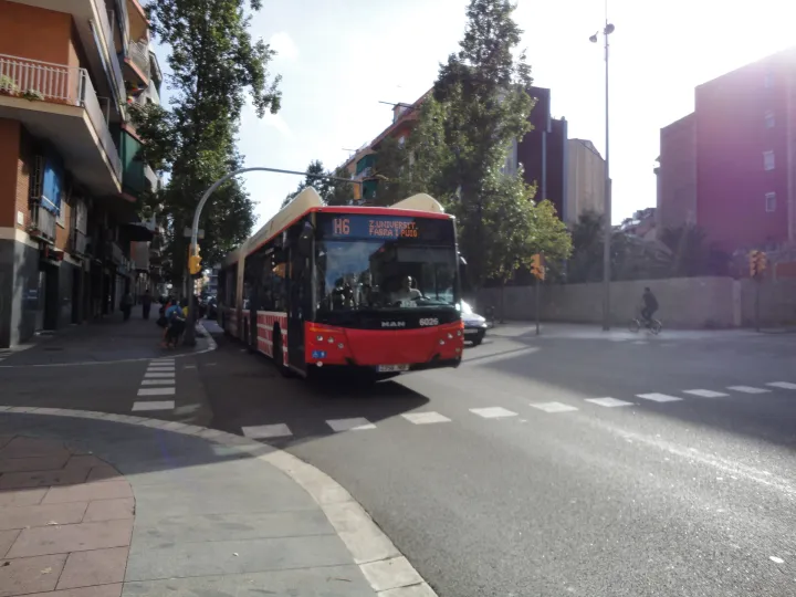 Un bus articulé rouge et blanc de la ligne H6 de TMB dans une avenue de Barcelone