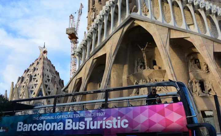 Um Ônibus Turístico de dois andares passa em frente à fachada da Natividade da Sagrada Família