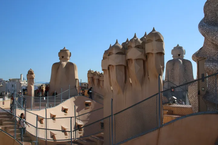 The rooftop terrace of Casa Milà and its sculptural chimneys under a blue sky