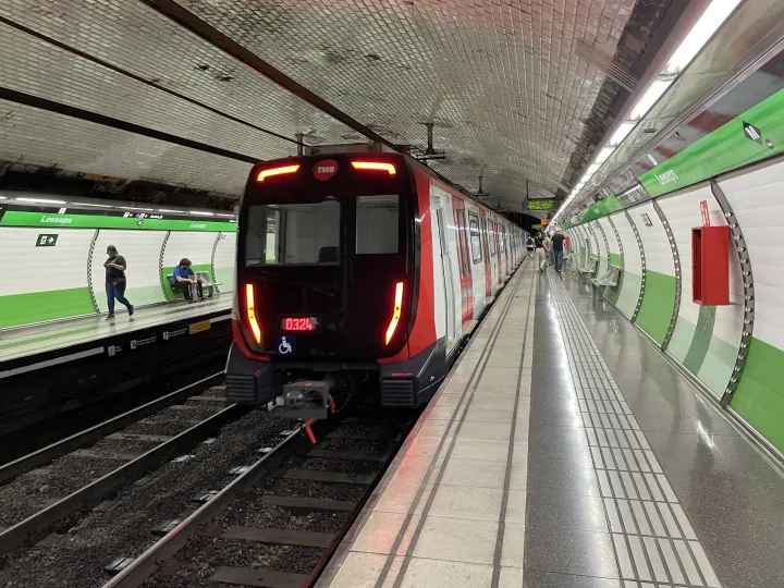 Um trem da linha verde L3 sai da estação de metrô Lesseps, com paredes revestidas de azulejos verdes